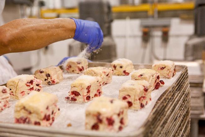 Photo of Sweet Sam's Worker Sprinkling Sugar on Scones